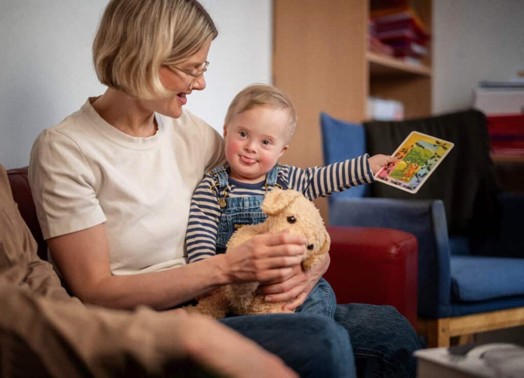 Mor med barn som har Downs syndrom sittende på fanget