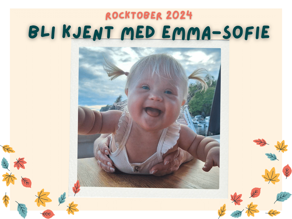 Baby med downs syndrom smiler til kamera mens hun ligger på magen