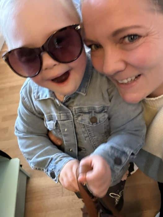 Smilende jente med solbriller sammen med smilende mamma